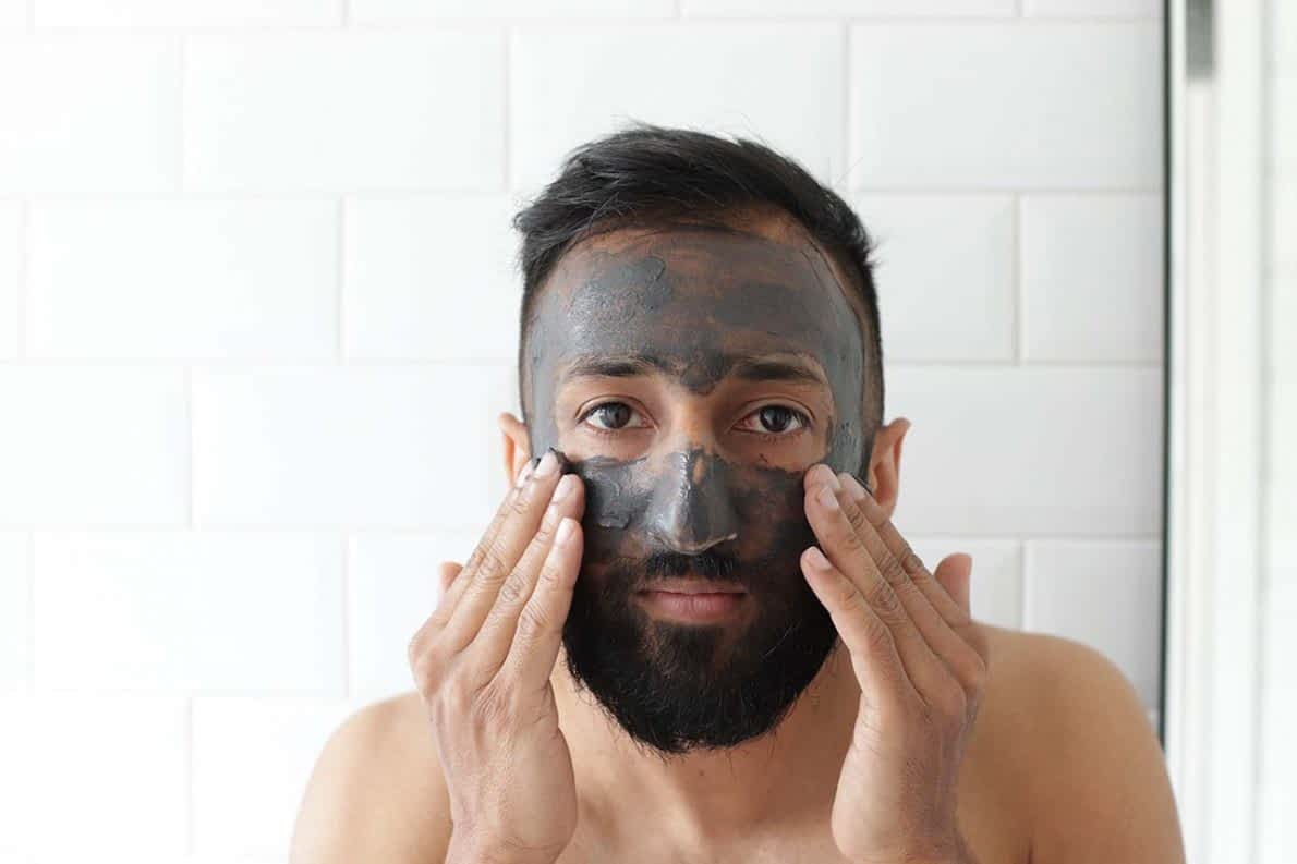 young man with black cosmetic mask on face and hands